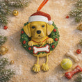 Load image into Gallery viewer, Dog Christmas ornament with a wreath and Santa hat on a decorative background with ornaments and a ball.