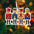 Load image into Gallery viewer, Four nutcracker ornaments with customizable name tags against a blurred Christmas tree background.