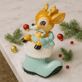 Load image into Gallery viewer, A glossy resin baby deer ornament features a cute fawn character sitting inside a soft pastel blue winter boot, holding a striped candy cane, with gentle antler details, smooth painted cartoon style finish, soft holiday lighting and blurred festive background, handwritten personalization showing the baby name on the boot and the year or Baby’s First Christmas text below, designed as a mostly 2D ornament with raised 3D details on the front only.