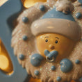 Load image into Gallery viewer, Decorative ornament with a baby face and blue hat on a blurred background