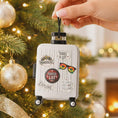 Load image into Gallery viewer, Small suitcase ornament with travel-themed stickers on a Christmas tree.