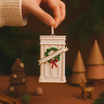Load image into Gallery viewer, Decorative Christmas ornament resembling a mailbox with a wreath and ribbon, held by a hand against a festive background.