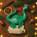 Load image into Gallery viewer, Green dinosaur ornament on a wooden surface with Christmas decorations