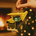 Load image into Gallery viewer, dump truck held by a hand with a warm, blurred background