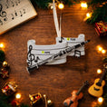 Load image into Gallery viewer, Decorative clarinet ornament with musical notes on a wooden surface with Christmas decorations.