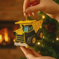 Load image into Gallery viewer, Yellow dump truck ornament held by a hand with a warm background