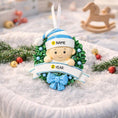 Load image into Gallery viewer, Personalized Baby Boy Christmas Ornament featuring a sweet child peeking from a festive green wreath with blue accents and polka dot bow. This ornament has a raised 3D front design with detailed holly leaves, textured elements, and dimensional lettering. The name is placed on the hat and the year on the banner. A meaningful keepsake for babyâs first Christmas, newborn gift, or holiday memory decoration for the Christmas tree.