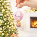 Load image into Gallery viewer, A personalized baby girl ornament featuring a cute bunny riding a pastel pink hot air balloon. Soft pink and white tones with delicate bow details create a sweet and cozy look. Handwritten personalization includes baby name and year. Mostly 2D ornament with raised 3D details on the front only, lightweight and easy to hang, perfect for baby first Christmas, nursery decor, and toddler keepsakes.