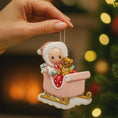 Load image into Gallery viewer, Personalized baby first Christmas ornament featuring a sweet baby sitting in a pastel pink sleigh holding a teddy bear. Handwritten baby name and year or Baby’s First Christmas text shown on the sleigh. Smooth resin finish with soft pastel tones, lightweight structure, mostly 2D ornament with raised 3D front details, designed for baby nursery themed Christmas tree decor and keepsake gifting.