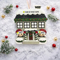 Load image into Gallery viewer, Personalized Christmas house ornament featuring a cozy winter home decorated with snow, wreaths, garlands, and festive details. Two smiling characters wearing Santa hats peek from the front, each customizable with a name, while the roof displays a year or family name. Designed with a detailed 3D raised front and smooth finish, this ornament is perfect for Christmas tree decor, family keepsakes, new home celebrations, and holiday gifting.