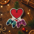 Load image into Gallery viewer, Gamer themed Christmas ornament featuring two game controllers connected with a heart design. Personalized with two custom names and a year or family name displayed on the ornament. Raised 3D details add texture and depth making it a unique holiday keepsake for gamer couples and gaming partners.
