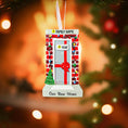 Load image into Gallery viewer, Decorative ornament for a new home with a door, tree, and gift box design, set against a blurred Christmas tree background.