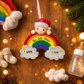 Load image into Gallery viewer, Personalized Christmas ornament with rainbow and baby elements on a wooden background.