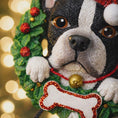Load image into Gallery viewer, Dog figurine ornament with a wreath and lights in the background
