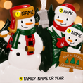 Load image into Gallery viewer, Personalized Christmas ornament with 3 snowmen , against a blurred festive background.