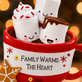 Load image into Gallery viewer, Red mug with marshmallows and text 'Family warms the heart' against a blurred warm light background