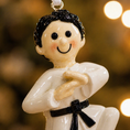 Load image into Gallery viewer, Decorative ornament of a martial artist in a white gi with a black belt against a blurred background.