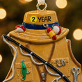 Load image into Gallery viewer, Decorative ornament of a fishing vest with a hat and fishing rod, against a blurred background.