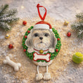 Load image into Gallery viewer, Dog-shaped Christmas ornament with a wreath and Santa hat on a decorative background with Christmas decorations.