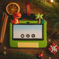 Load image into Gallery viewer, Green toy tablet ornament with dinosaur figure on a wooden surface with Christmas decorations