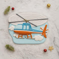 Load image into Gallery viewer, Cookie shaped like a helicopter on a marble surface with decorative elements.
