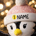Load image into Gallery viewer, Personalized Baby Penguin First Christmas Ornament featuring a sweet penguin wearing a soft pink winter hat, sitting on a snowy base. The babyâs name is displayed on the hat and the year is placed on the belly, creating a meaningful keepsake for a newbornâs first holiday season. With bright yellow feet, soft winter details, and charming 3D design, this ornament is perfect for baby girls celebrating their very first Christmas and makes a thoughtful holiday gift for new parents.