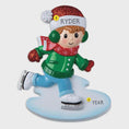 Load image into Gallery viewer, This personalized ice skating boy ornament features a cheerful winter skater wearing festive holiday clothing and gliding across an icy base. The design includes a custom name on the hat and a year displayed on the base, making it a perfect keepsake for celebrating winter memories, first Christmas moments, or a child’s love for ice skating and winter sports.