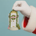 Load image into Gallery viewer, Decorative Christmas ornament of a door with wreath held by a gloved hand against a light blue background
