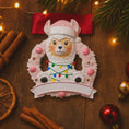 Load image into Gallery viewer, Personalized pink llama Christmas ornament featuring a cute white llama wrapped in colorful holiday lights, framed in a glittery wreath with pink accents. The top hat band can be customized with a name, while the bottom banner allows space for year or Babyâs 1st Christmas. Designed in soft pink and festive tones, this resin baby girl Christmas ornament makes a meaningful keepsake gift for celebrating a newbornâs first holiday season.