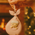 Load image into Gallery viewer, Decorative ornament of a baby in a pink blanket with bunny ears, held against a warm, blurred background.