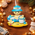 Load image into Gallery viewer, Personalized Beach Baby Christmas Ornament featuring a cheerful toddler sitting on the sand with a beach hat, float, bucket, and shovel. This detailed 3D front design includes raised elements, bright summer colors, and textured sand base for added depth. The name is placed on the hat and the year on the sandy base. A perfect keepsake for baby’s first beach trip or summer memory, ideal for Christmas tree decor or a thoughtful holiday gift for new parents.