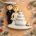 Load image into Gallery viewer, Wedding cake topper with bride and groom figurines on a decorative background with Christmas elements.