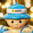 Load image into Gallery viewer, Personalized Beach Baby Christmas Ornament featuring a cheerful toddler sitting on the sand with a beach hat, float, bucket, and shovel. This detailed 3D front design includes raised elements, bright summer colors, and textured sand base for added depth. The name is placed on the hat and the year on the sandy base. A perfect keepsake for baby’s first beach trip or summer memory, ideal for Christmas tree decor or a thoughtful holiday gift for new parents.