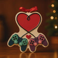 Load image into Gallery viewer, Gamer themed Christmas ornament featuring two game controllers connected with a heart design. Personalized with two custom names and a year or family name displayed on the ornament. Raised 3D details add texture and depth making it a unique holiday keepsake for gamer couples and gaming partners.
