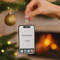 Load image into Gallery viewer, Phone-shaped ornament with 'Samantha' and 'Year' text, held by a hand against a Christmas tree background.