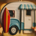 Load image into Gallery viewer, Close-up of a toy camper with a surfboard attached, blurred background