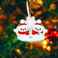 Load image into Gallery viewer, Christmas ornament with two cartoon characters in winter attire against a blurred Christmas tree background.