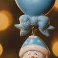 Load image into Gallery viewer, Decorative snowman ornament with blue hat and bow tie against a blurred light background