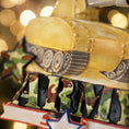 Load image into Gallery viewer, A resin Army tank ornament in bold yellow features a cartoon style military tank with detailed black tracks and raised cannon, camouflage green ARMY lettering across the front, a star accent and American flag inspired base, surrounded by snow texture and festive holiday elements, with handwritten personalization showing one name on the left banner and the year on the right banner, designed as a mostly 2D ornament with raised 3D details on the front only for lightweight Christmas tree decor.