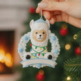Load image into Gallery viewer, Personalized baby boy llama ornament featuring a cute smiling llama wearing a winter hat and surrounded by a festive wreath with colorful holiday lights. Soft blue and white tones create a cozy winter look. Handwritten personalization includes baby name and Baby’s First Christmas with year. Mostly 2D ornament with raised 3D details on the front only, lightweight and perfect for Christmas trees, nursery decor, and baby keepsakes.