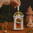 Load image into Gallery viewer, Decorative Christmas ornament resembling a small building with a hand holding it, set against a festive background.