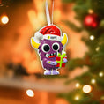 Load image into Gallery viewer, Purple monster Christmas ornament with Santa hat and gift, blurred Christmas tree background