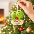 Load image into Gallery viewer, Decorative Christmas ornament with two green olives and a heart, held in front of a lit Christmas tree.