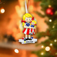 Load image into Gallery viewer, Personalized Christmas ornament of a girl in a patriotic dress holding a baby, with a blurred festive background.
