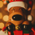 Load image into Gallery viewer, Toy reindeer with a Santa hat and bell against a blurred festive background