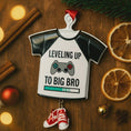 Load image into Gallery viewer, Decorative ornament shaped like a t-shirt with text and graphics on a wooden surface with festive items.