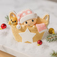 Load image into Gallery viewer, Personalized Baby Girl First Christmas Ornament featuring a detailed 3D front design with a sweet baby resting inside a woven basket, pink nightcap, teddy bear, and hanging star for the year. The babyâs name is added on the hat and the year on the star, creating a meaningful keepsake. Soft pink tones, cozy textures, and dimensional elements make it perfect for newborn girl gifts, baby shower presents, and treasured first Christmas tree memories.