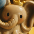 Load image into Gallery viewer, Close-up of a toy elephant with a blue hat and yellow crown.