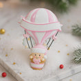 Load image into Gallery viewer, Personalized baby first Christmas ornament featuring a soft pastel pink hot air balloon design with a sweet baby character inside the basket. Handwritten baby name and year or Baby’s First Christmas text displayed on the balloon. Smooth resin finish with gentle glitter accents, nursery themed colors, lightweight structure, mostly 2D ornament with raised 3D details on the front only, designed for baby Christmas tree decor and keepsake gifting.