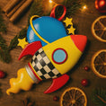 Load image into Gallery viewer, Colorful rocket-shaped ornament on a wooden surface with Christmas decorations.